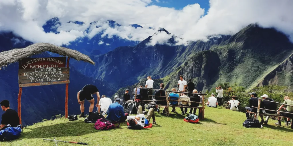 Turistas relaxando no mirante de Llactapata, um mirante com vistas deslumbrantes das montanhas do Vale Sagrado. Esta rota fica perto da Trilha Inca e de Machu Picchu, ideal para caminhantes que buscam paisagens espetaculares no Peru.