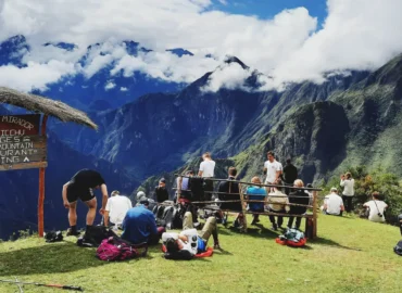 Turistas relaxando no mirante de Llactapata, um mirante com vistas deslumbrantes das montanhas do Vale Sagrado. Esta rota fica perto da Trilha Inca e de Machu Picchu, ideal para caminhantes que buscam paisagens espetaculares no Peru.
