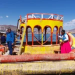 Totora reed raft decorated in the shape of a dragon on Lake Titicaca, Peru. Traditional floating reed boat used by the Uros people for transportation and tourism. A woman in traditional Aymara dress and a visitor pose on the raft, overlooking the lake and mountains. A unique cultural experience in Puno, ideal for exploring floating life and Andean heritage.