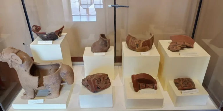 Exposição de artefatos arqueológicos no Museu Pucará, Peru. Cerâmicas pré-incas da cultura Colla, incluindo vasos, jarros e figuras de animais. Fragmentos de potes e xícaras decorados com motivos geométricos. Um destino cultural em Puno, ideal para aprender sobre a história antiga e a arte andina do sul do Peru.