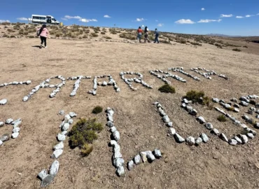 Letras de pedra com a inscrição "Cachoeira de Pillanes" no deserto, Peru – turistas visitando o mirante natural no sul do país com paisagens áridas e montanhas ao fundo