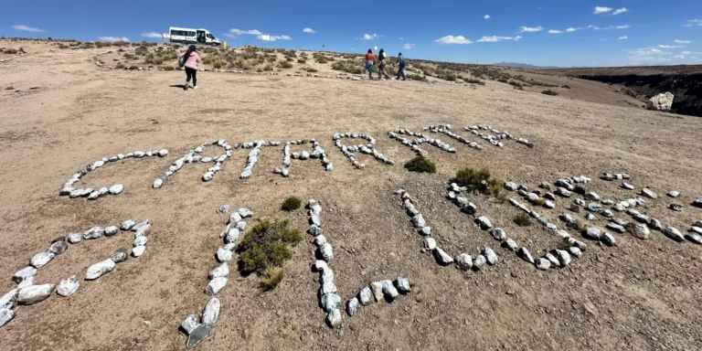 Letras de pedra com a inscrição "Cachoeira de Pillanes" no deserto, Peru – turistas visitando o mirante natural no sul do país com paisagens áridas e montanhas ao fundo