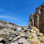 Cachoeira Pillones no sul do Peru – viajantes caminham por um cânion com cachoeiras naturais, rochas e um rio entre as montanhas do planalto andino.