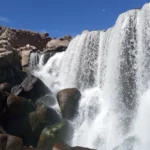 Cachoeiras de Pillones, no planalto andino do Peru – uma viajante tirando fotos com seu celular das cachoeiras naturais entre as rochas e montanhas no sul do país.