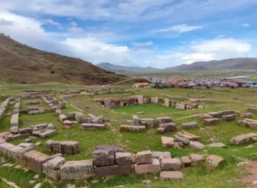 Ruínas arqueológicas de Pucará de Lampa, Peru. Estruturas de pedra pré-incas em um vale verdejante, construídas pela cultura Colla. Um sítio histórico no departamento de Puno, ideal para explorar a história antiga e a arquitetura andina do sul do Peru. Vista panorâmica com montanhas e uma comunidade local ao fundo.