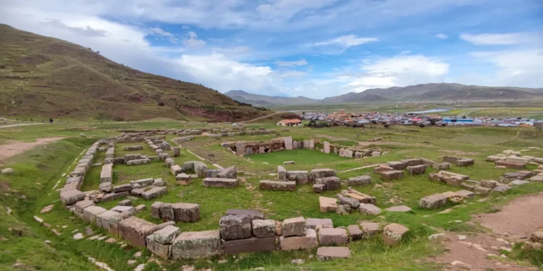 Ruínas arqueológicas de Pucará de Lampa, Peru. Estruturas de pedra pré-incas em um vale verdejante, construídas pela cultura Colla. Um sítio histórico no departamento de Puno, ideal para explorar a história antiga e a arquitetura andina do sul do Peru. Vista panorâmica com montanhas e uma comunidade local ao fundo.