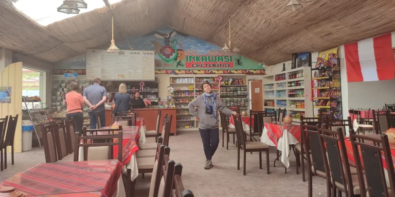 Interior do restaurante Inkawasi em Pampa de los Arrieros, Arequipa – um café temático com decoração andina, mesas com toalhas tradicionais e turistas apreciando comida típica peruana.