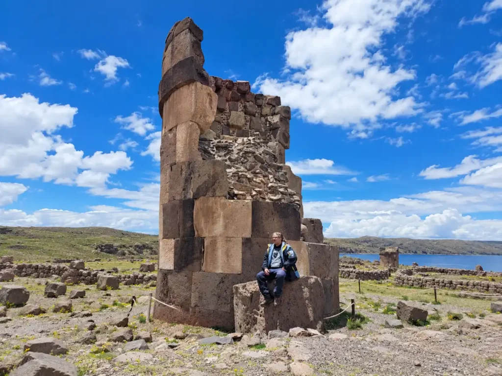 Turista junto a una chullpa de Sillustani con el lago Umayo y paisaje altoandino al fondo, Puno, Perú